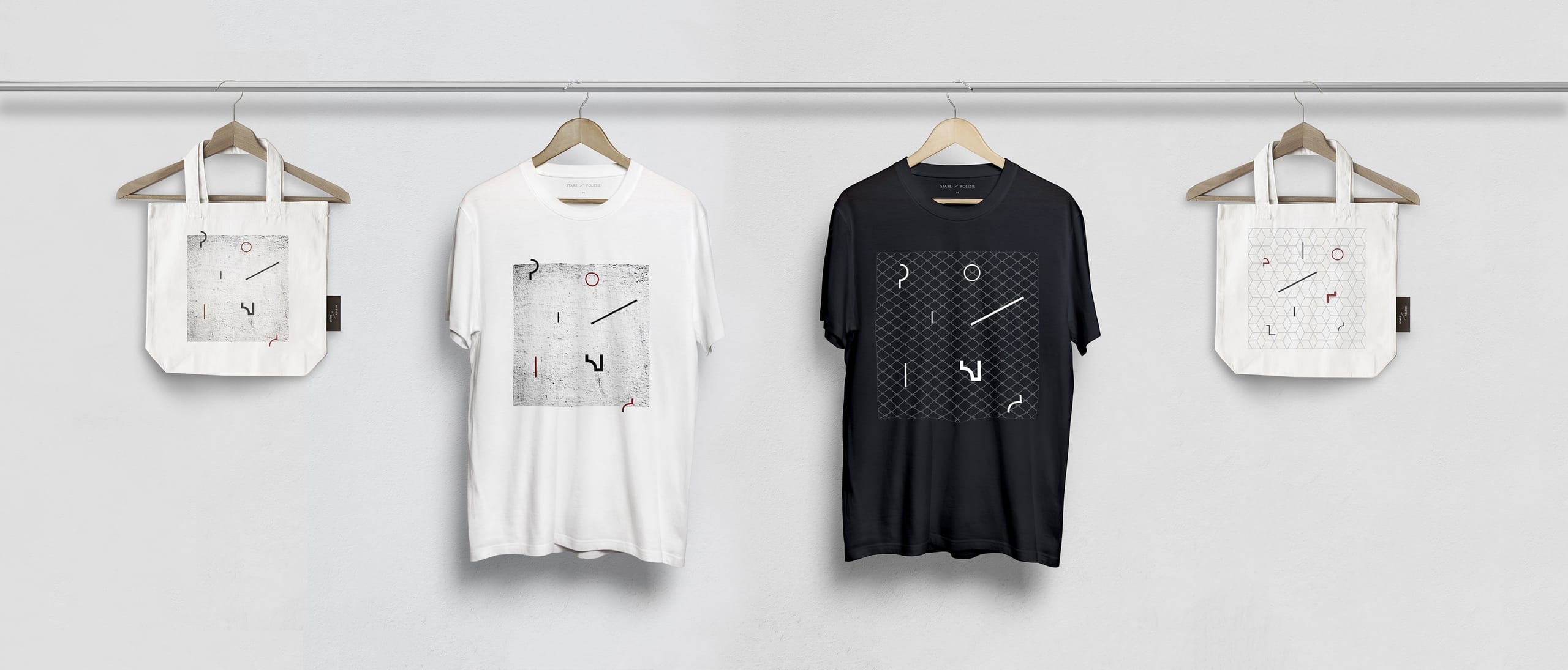 Tote bags and T-shirts on a rail printed with scattered logotype letters and the district pattern