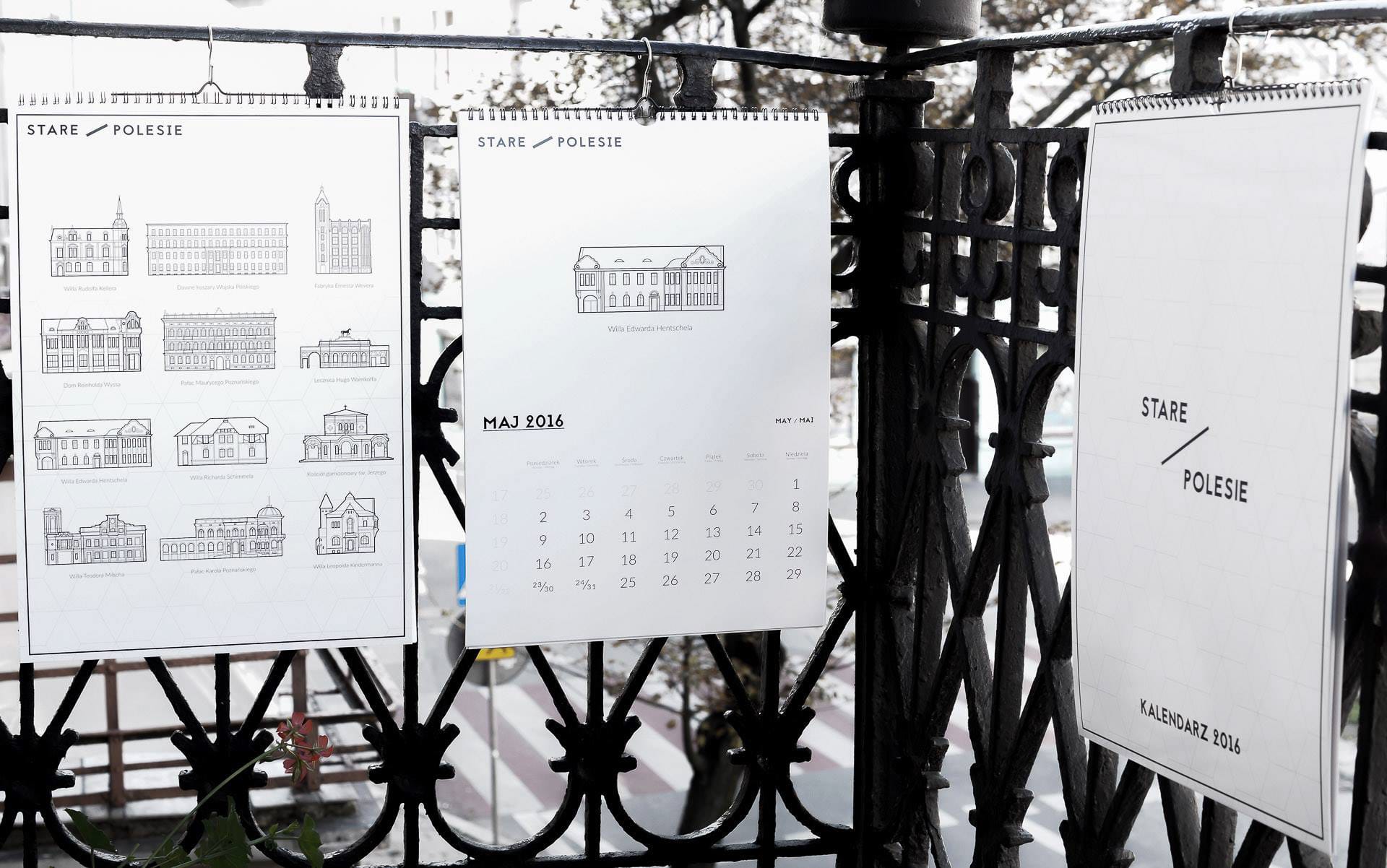 2016 calendars hung on a wrought-iron fence outdoors, showing the May page and cover
